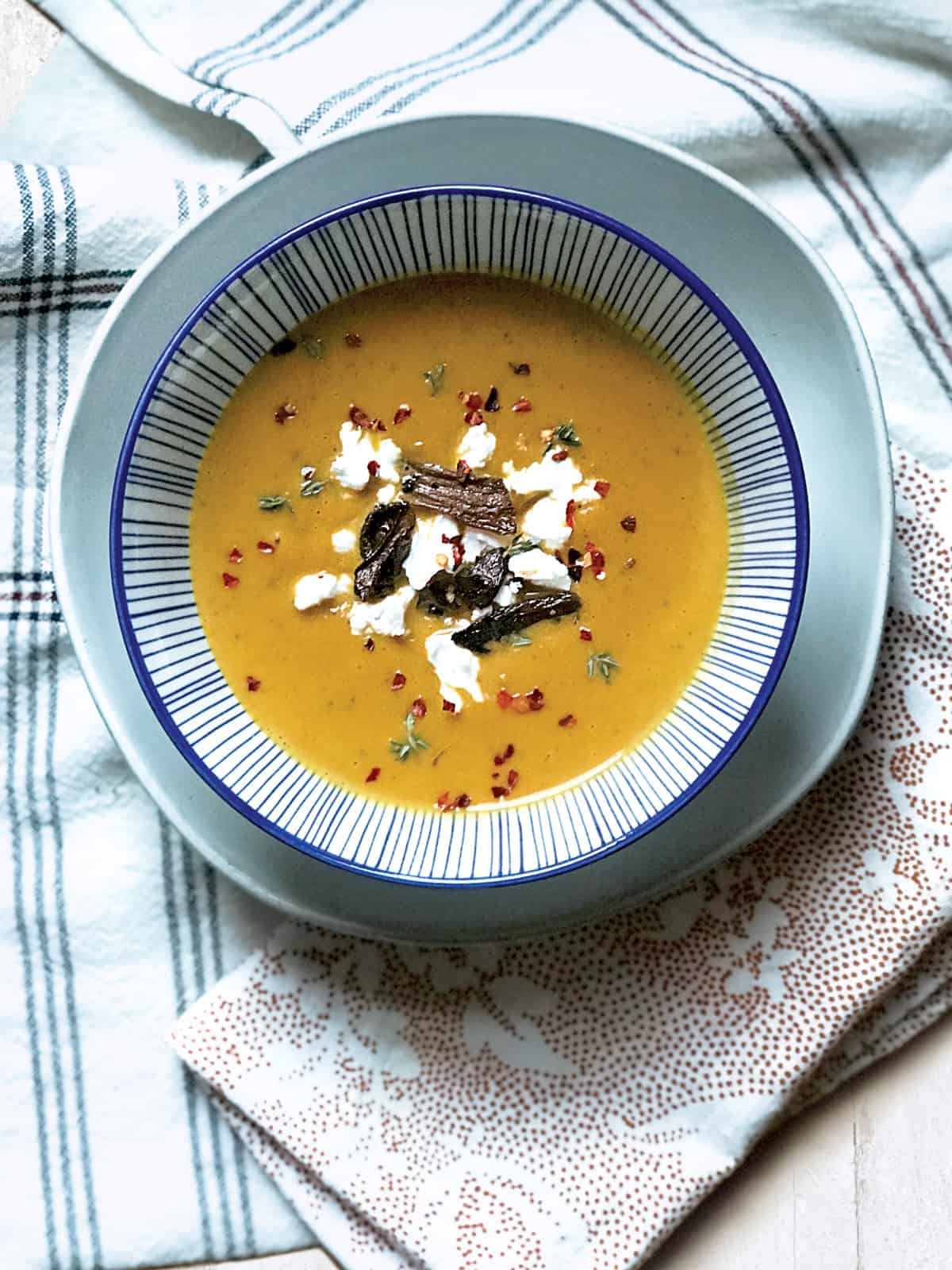 A bowl of red kabocha soup and some cloth napkins.