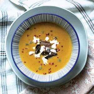 A bowl of red kabocha soup and some cloth napkins.