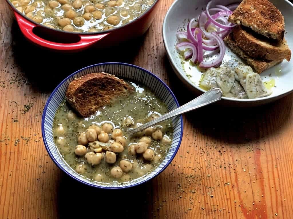 A bowl with Greek chickpea soup and a piece of bread.