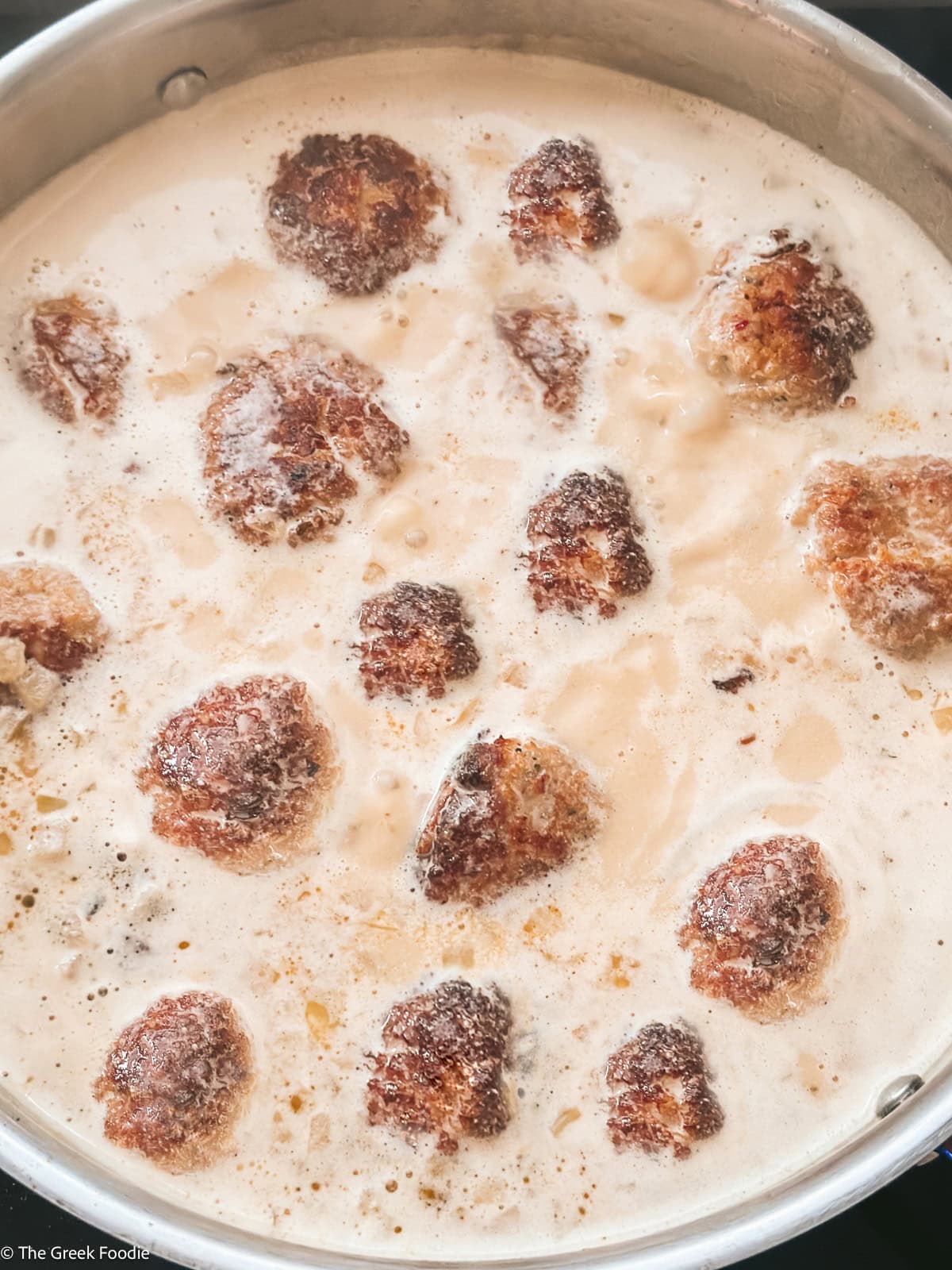 Low-carb turkey meatballs simmering in a creamy gravy sauce in a skillet.