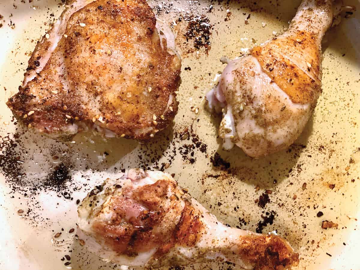 Pieces of chicken searing in olive oil.