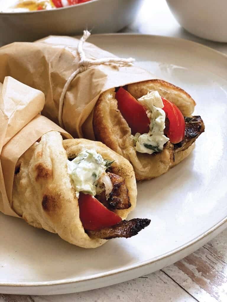 Two souvlaki wrapped in paper on a plate.