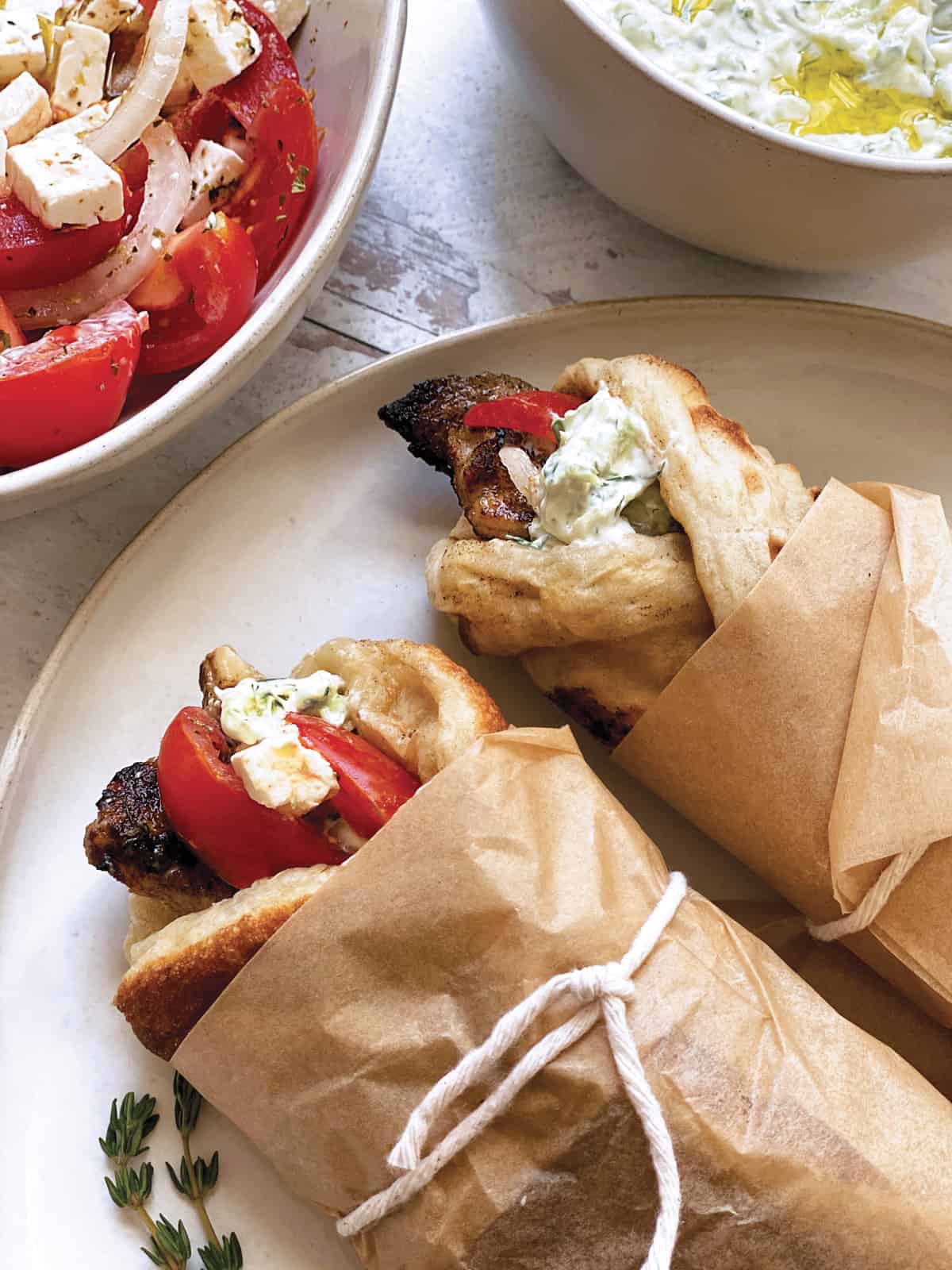 Two souvlaki wrapped in paper on a plate.