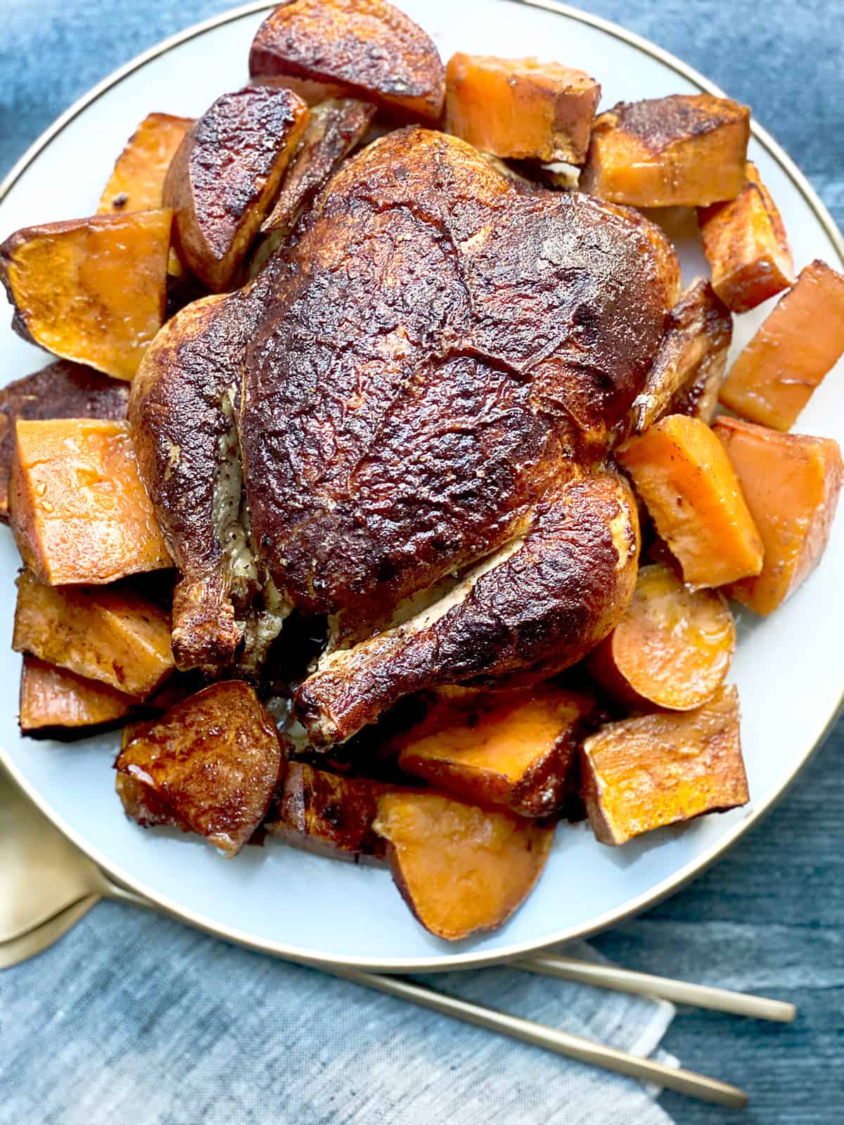 Roasted cinnamon chicken on a platter with serving utensils.