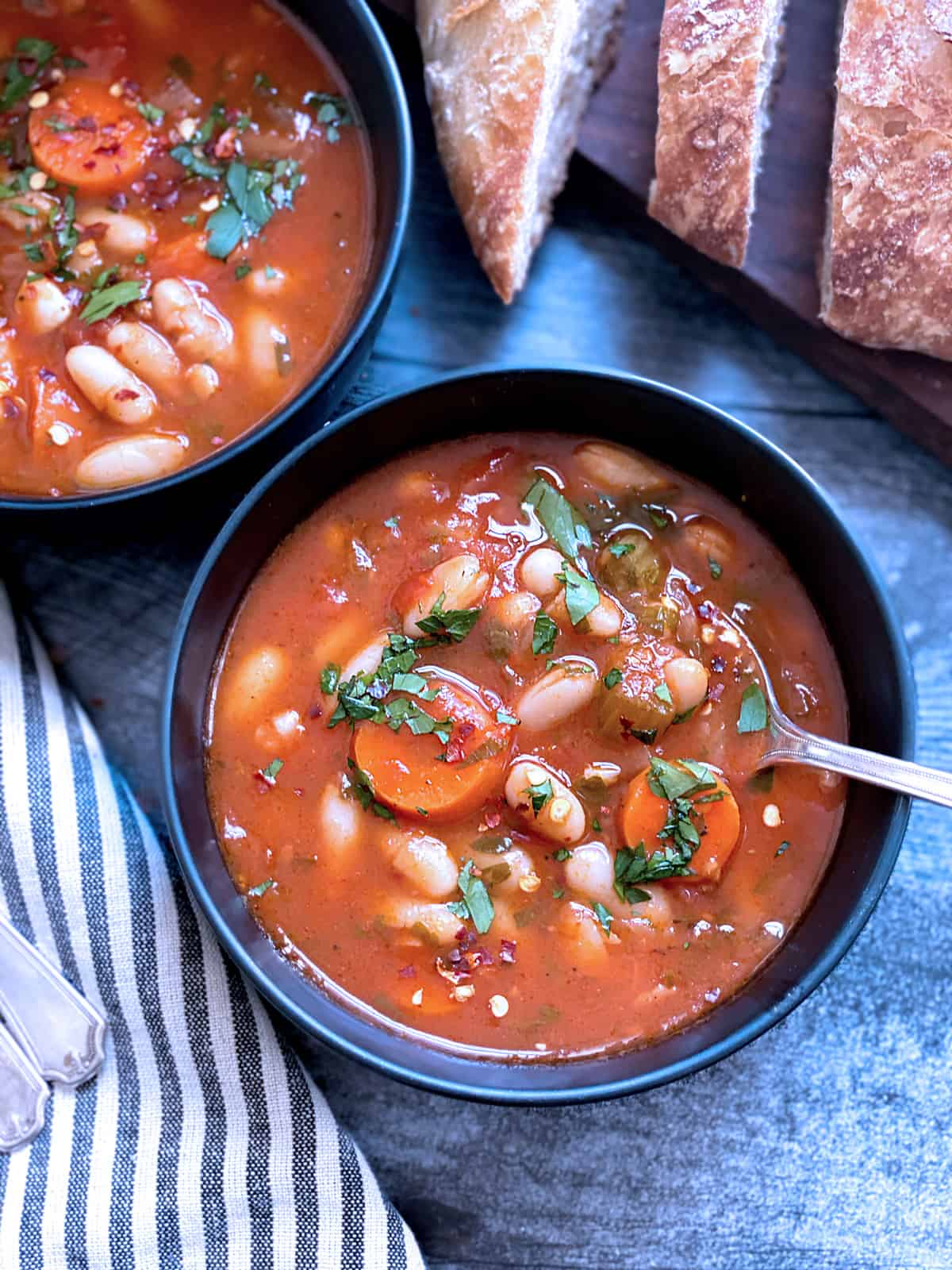 Two bowls with fasolada-greek white bean soup and bread.