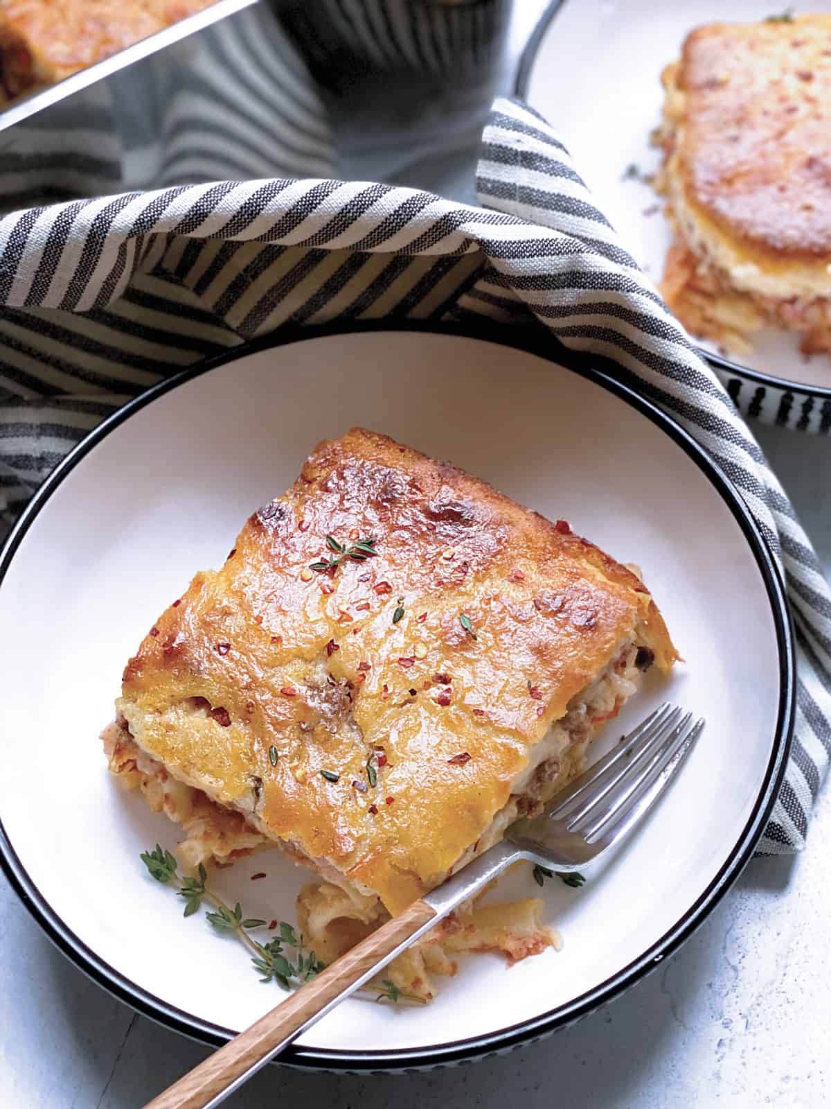 A plate with a piece of Pastitsio-Greek lasagna and a fork.