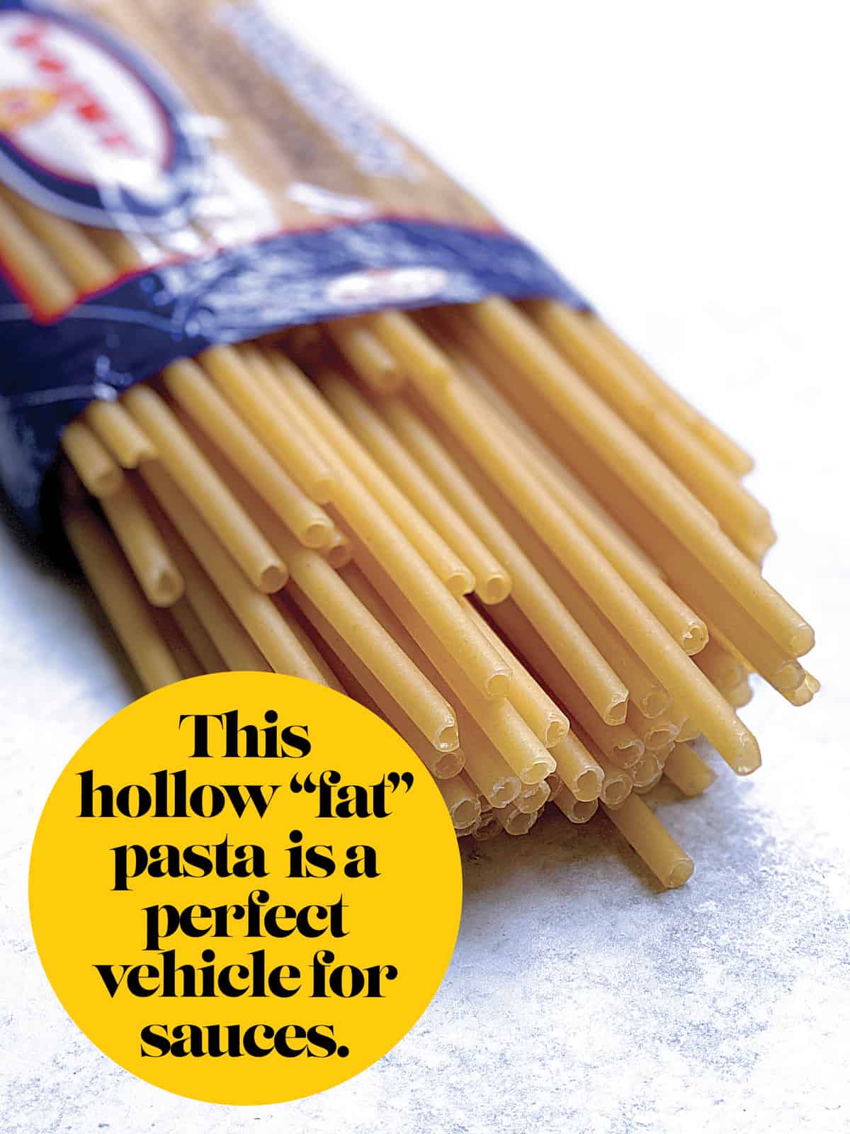 An open pack of pasta with some long macaroni showing.