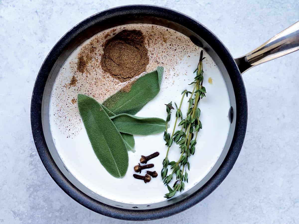 Sauce pan with cream, fresh herbs and spices.