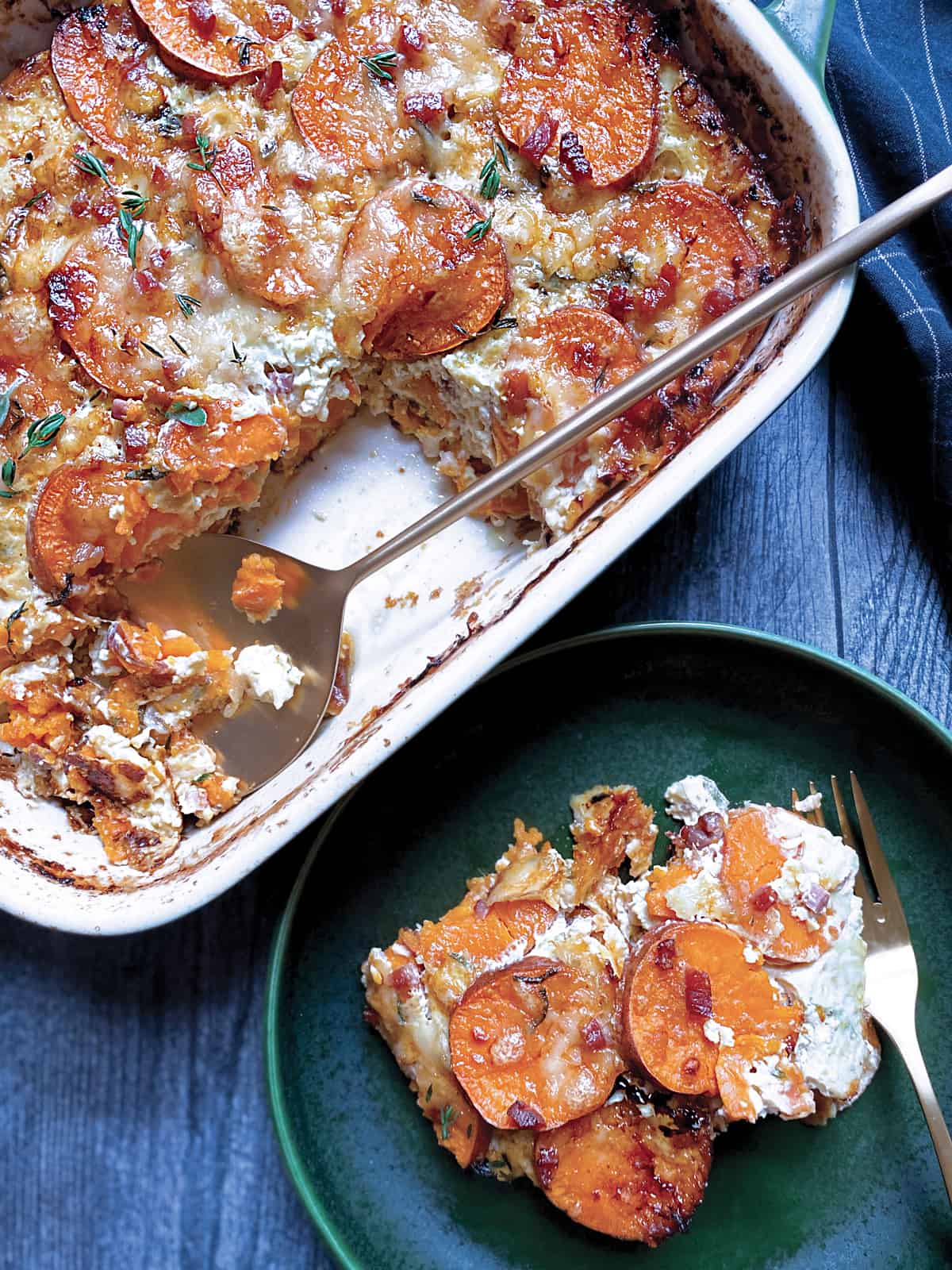 A baking pan with sweet potato au gratin and a gold serving utensil and a piece served on a green plate.