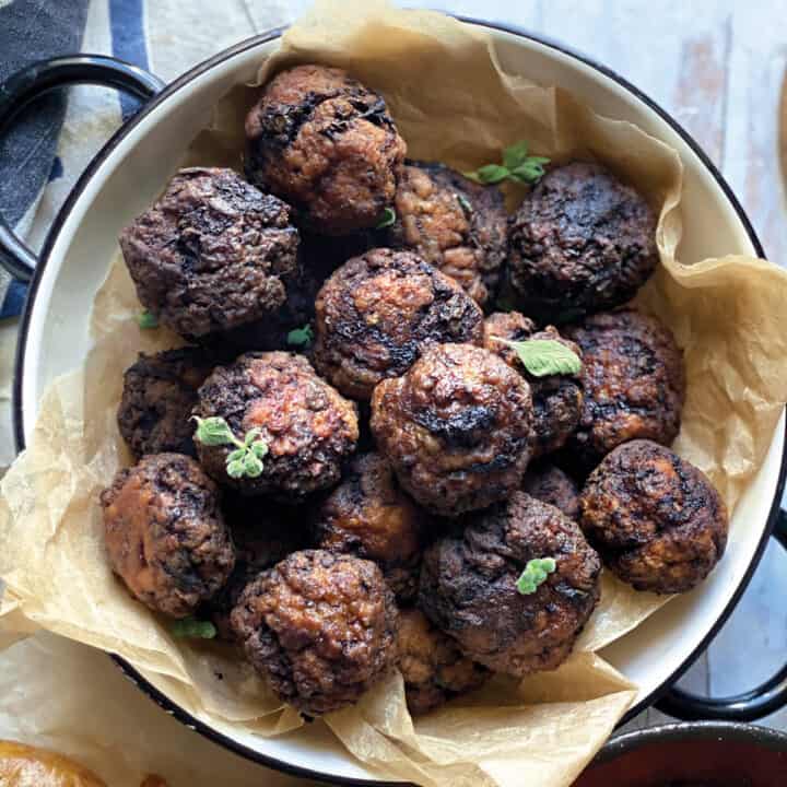 A plate with handles full of meatballs bon parchment paper.