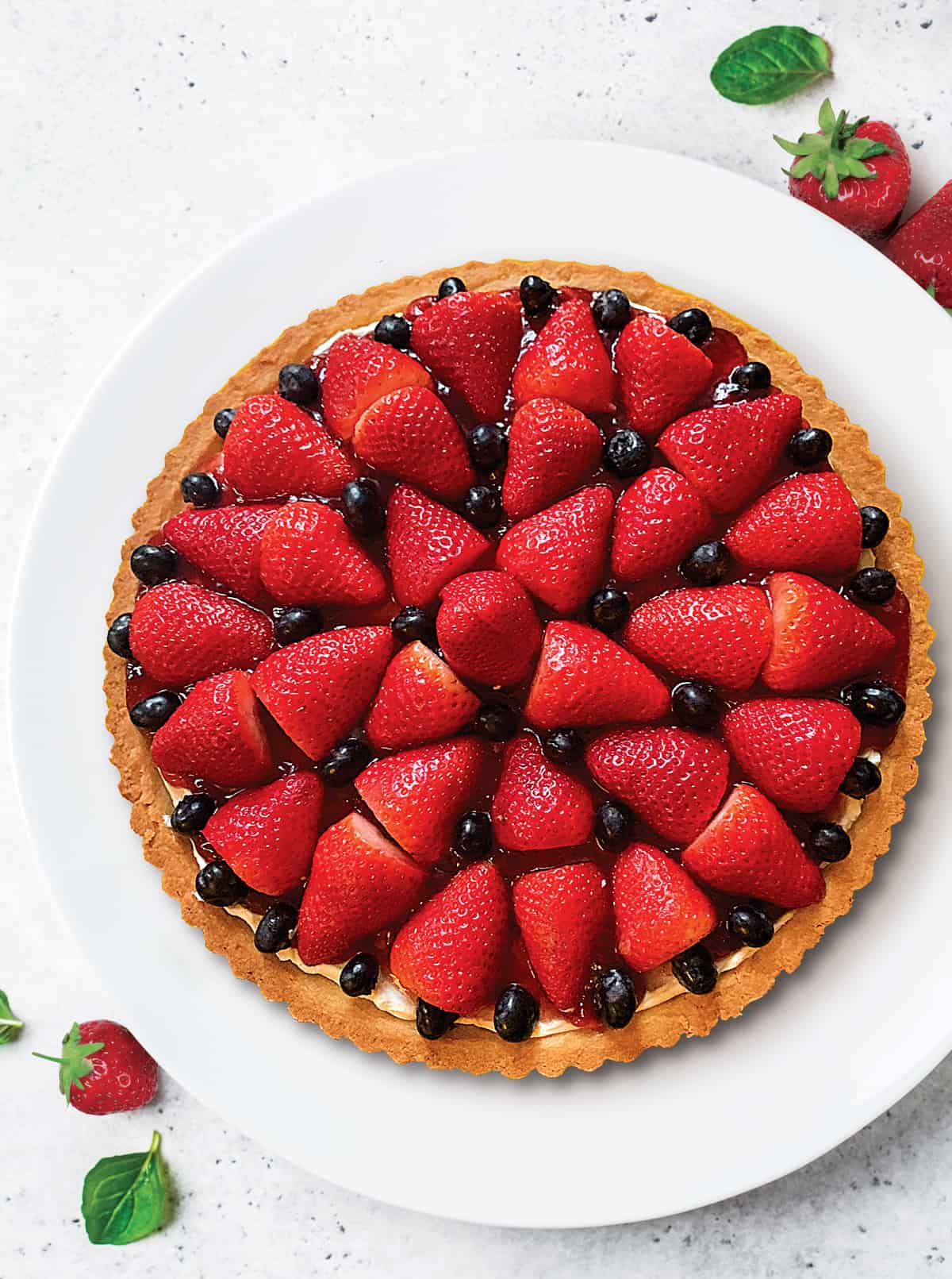 A tart with strawberries and blackberries on a white plate.