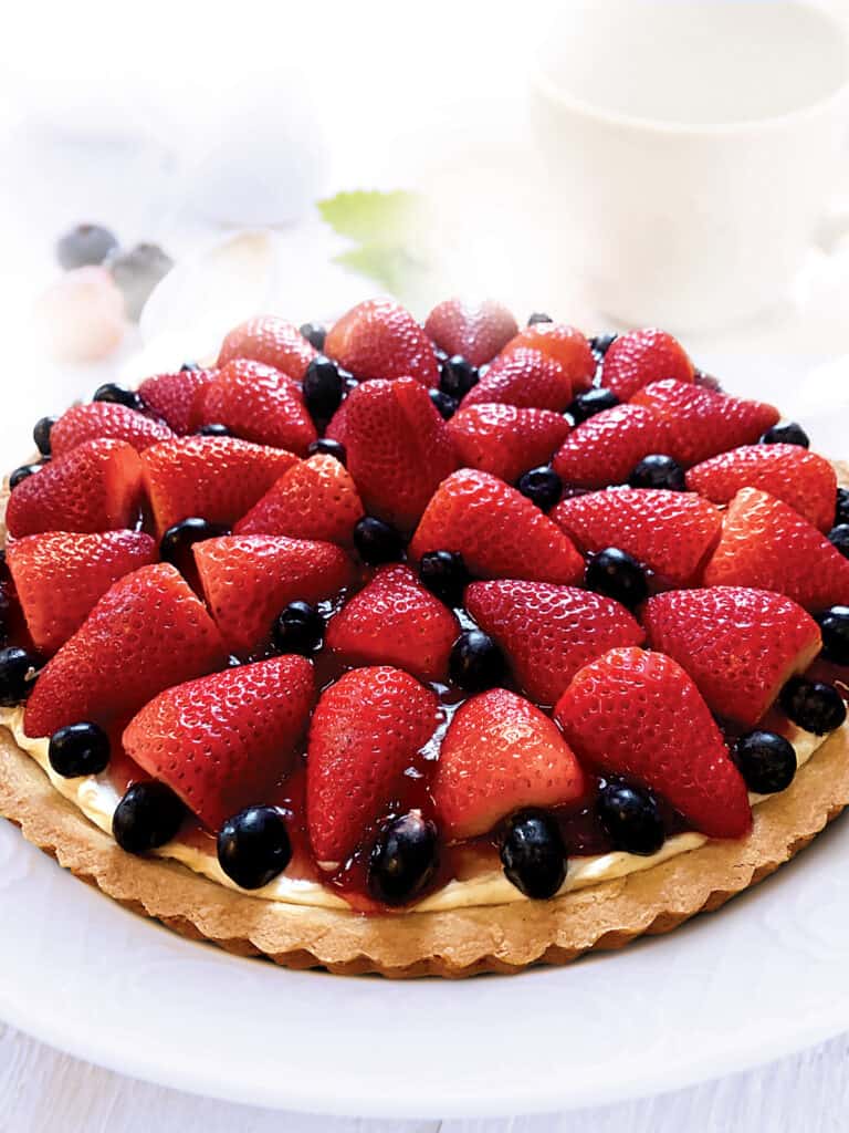 A berry tart with strawberries and blackberries on a white plate.