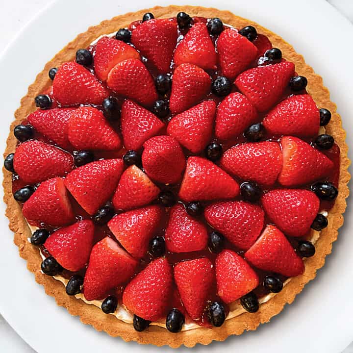 A tart with strawberries and blackberries on a white plate.