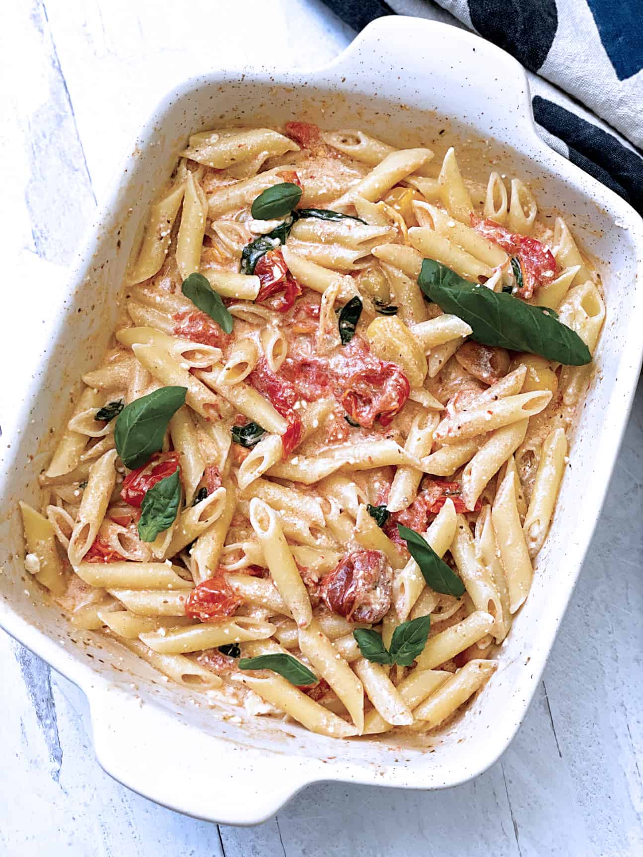 A baking pan with pasta, roasted cherry tomatoes, melted baked feta cheese.