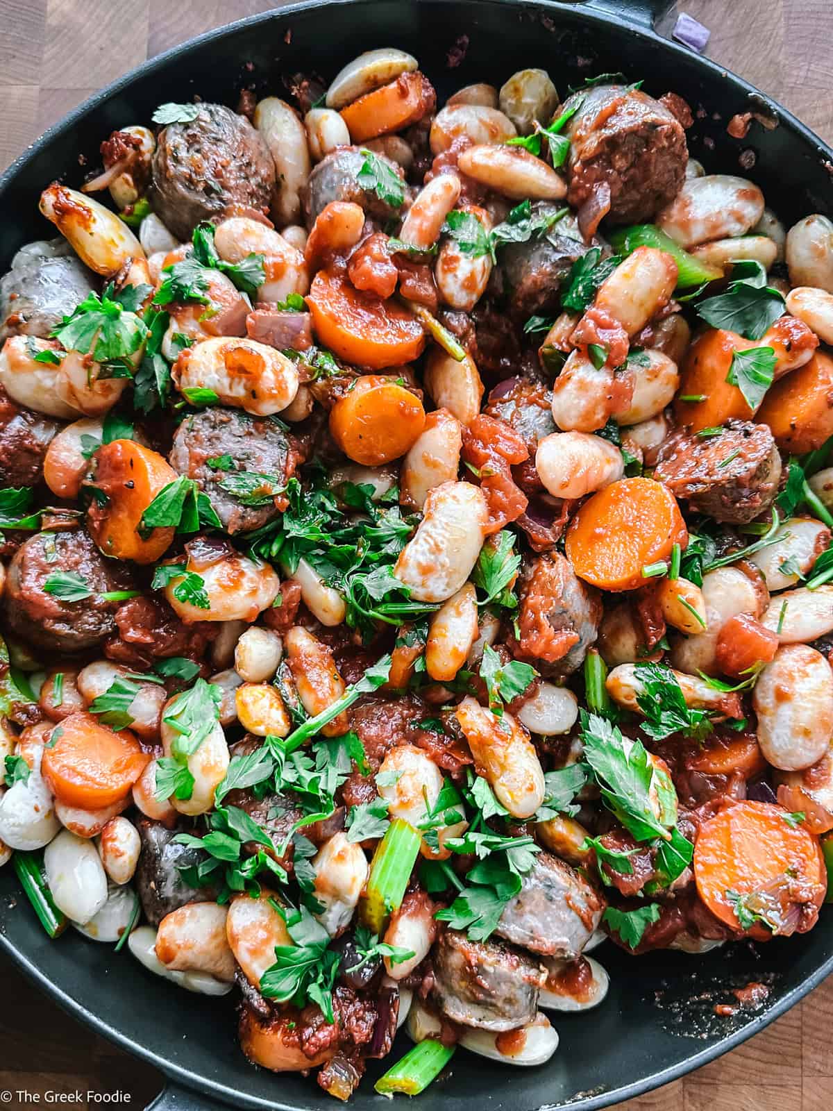 Gigantes beans, sausage, and vegetables combined with herbs in the pan