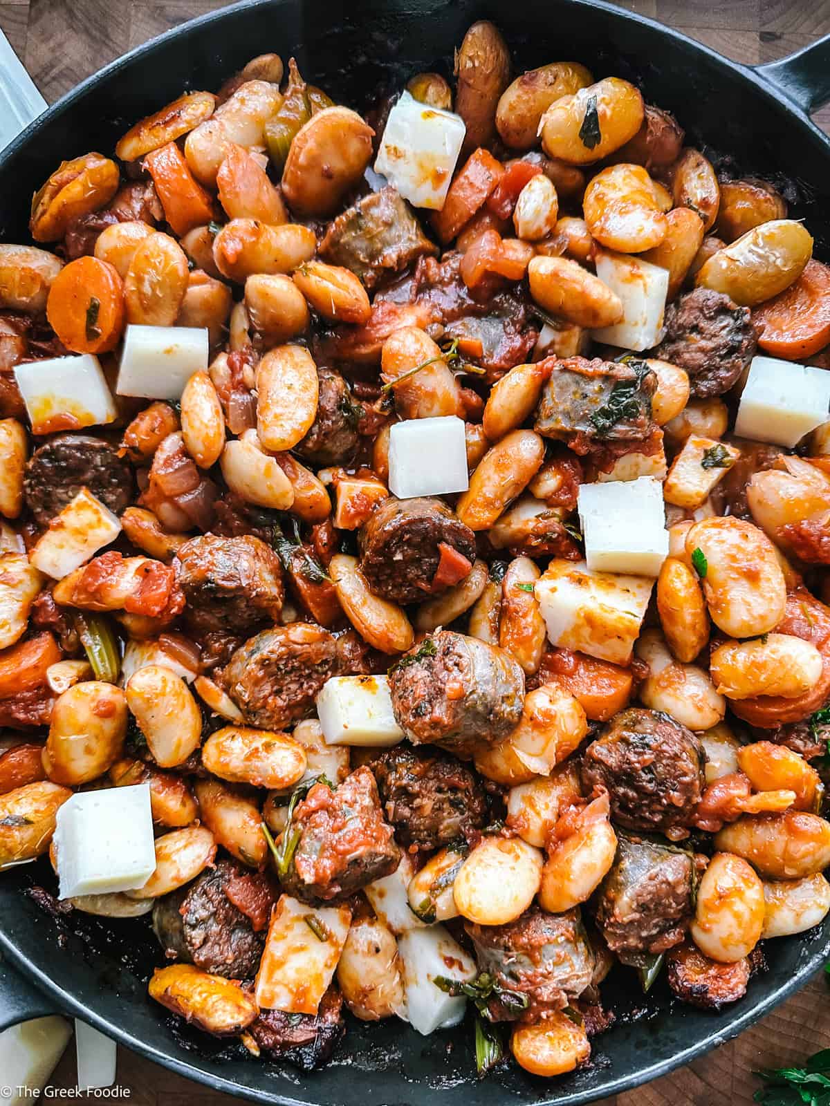 Gigantes plaki ready for the oven with graviera cheese cubes on top