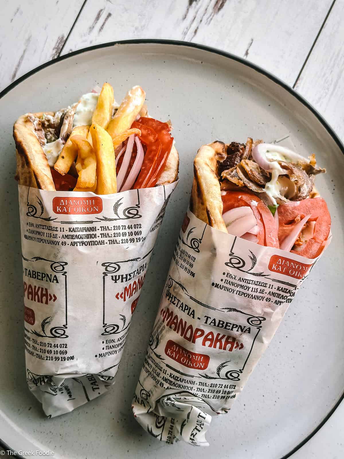 Two rolled gyros souvlaki, one with fries, the other without, on a plate.