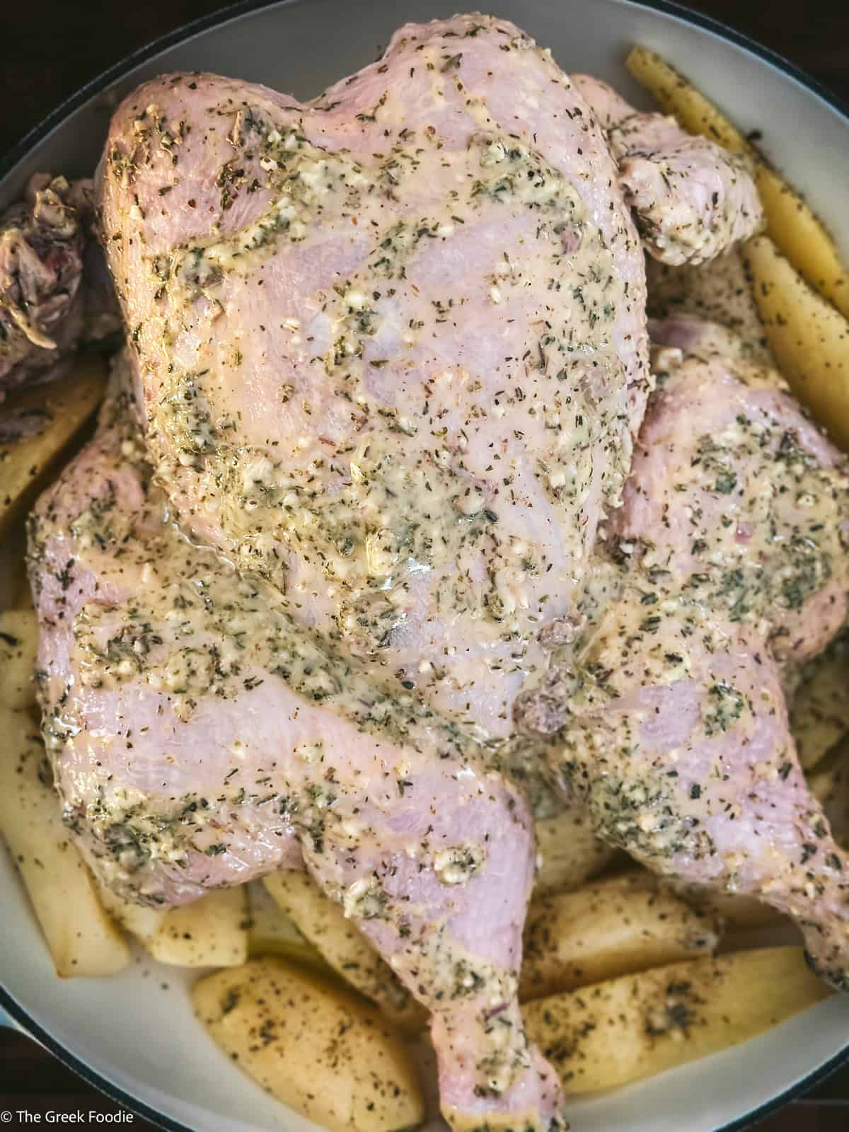 Greek spatchcocked chicken over potatoes ready for the oven