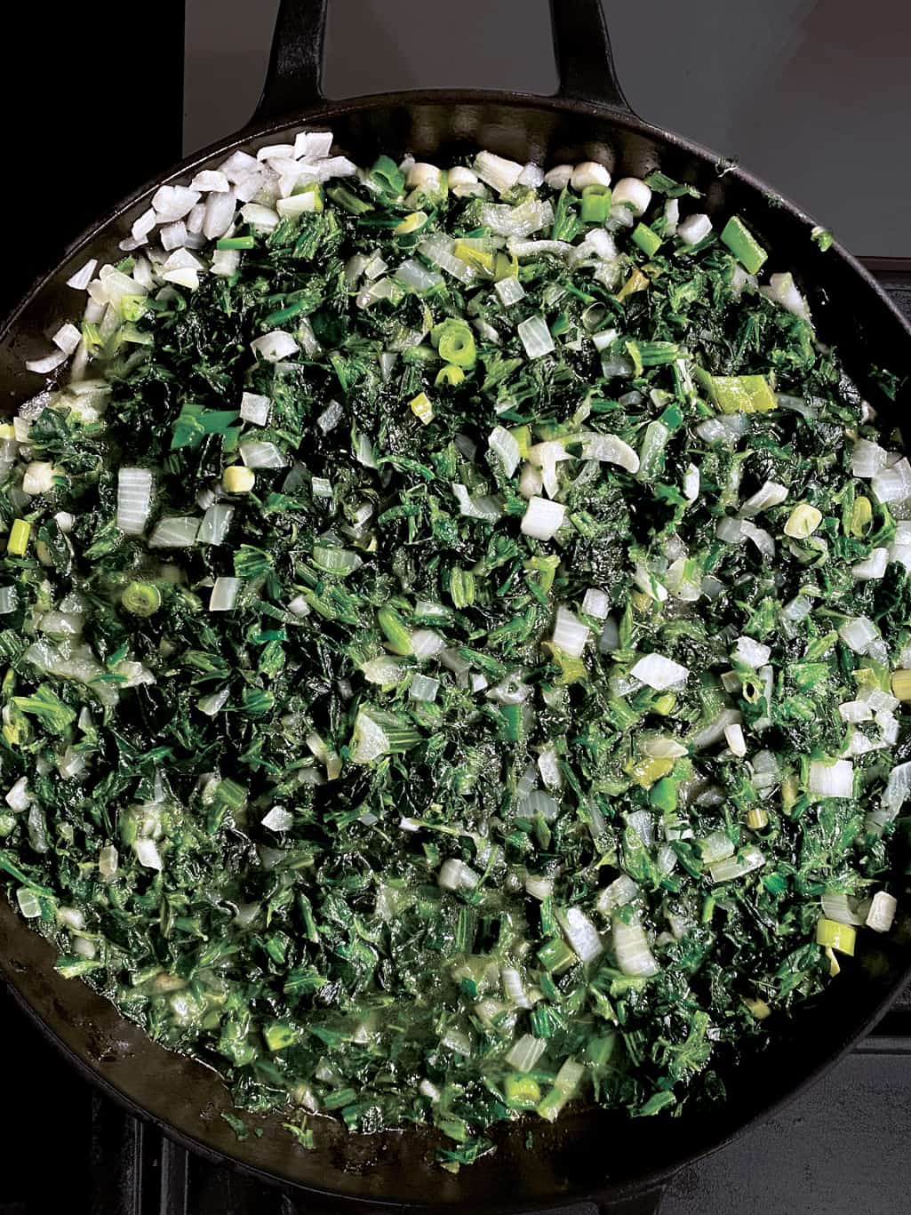 Diced onion, spinach and scallions in a pan.