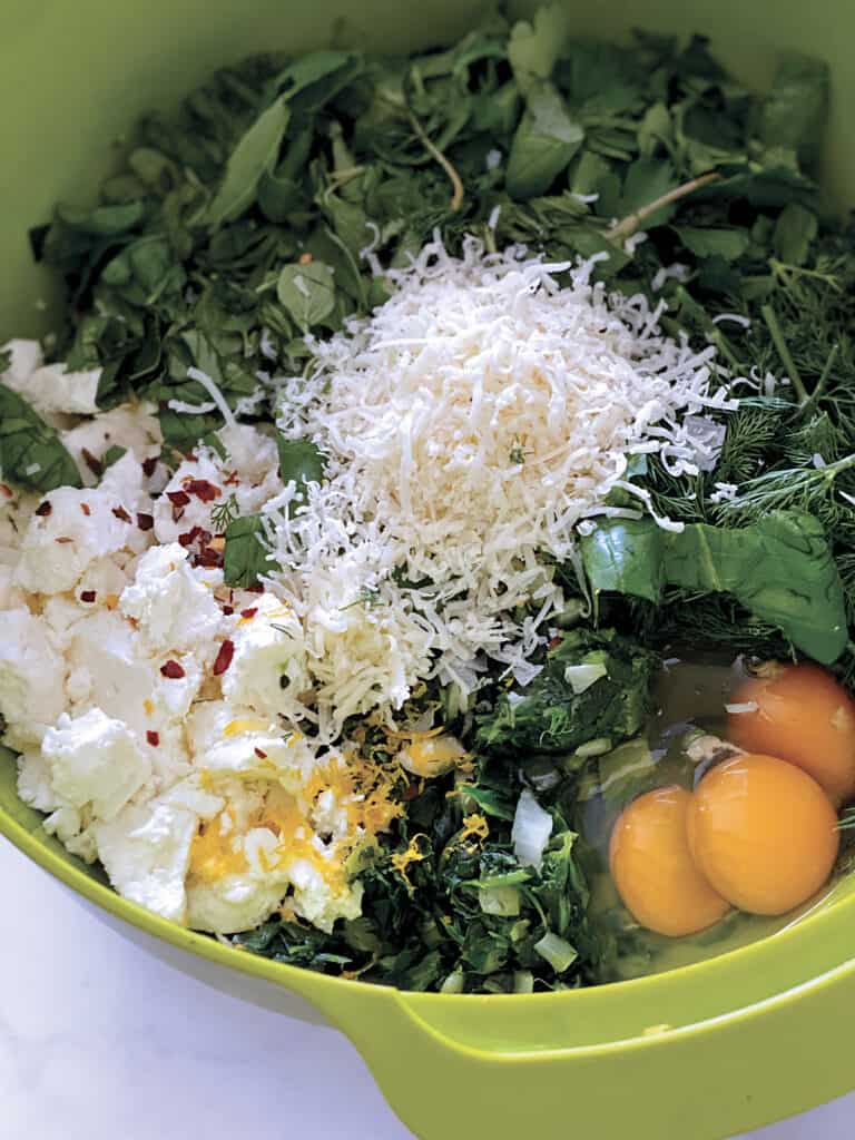 greens, eggs, feta lemon zest in a green bowl.