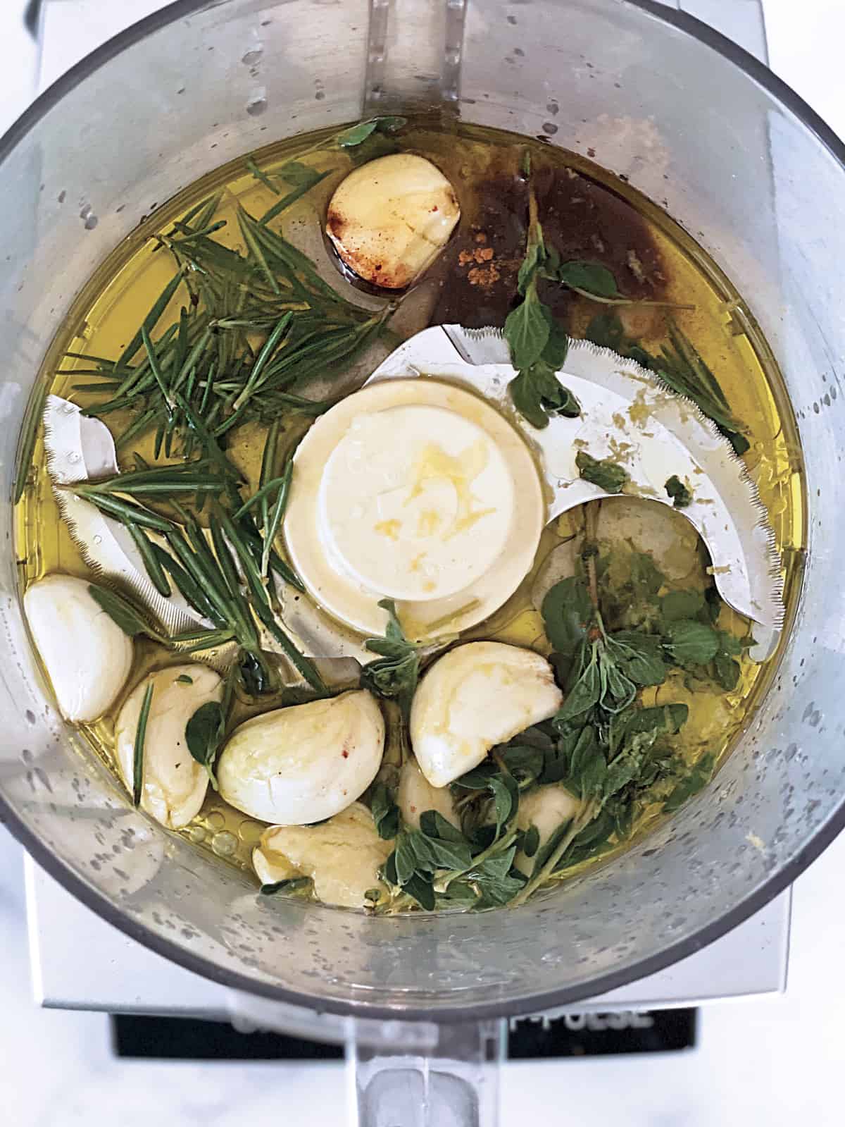 Garlic and herbs in a food processor with olive oil.