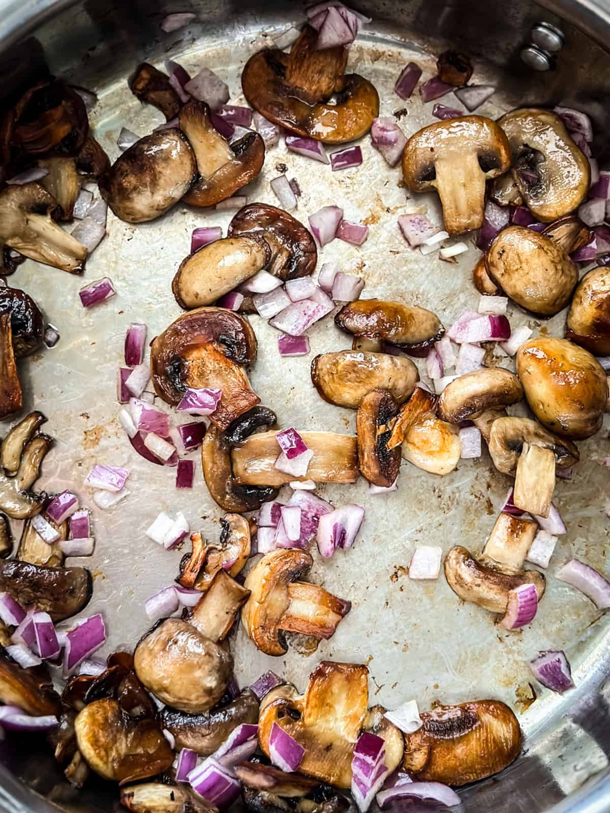 Sliced mushrooms, diced onions and garlic sauteing in a skillet.