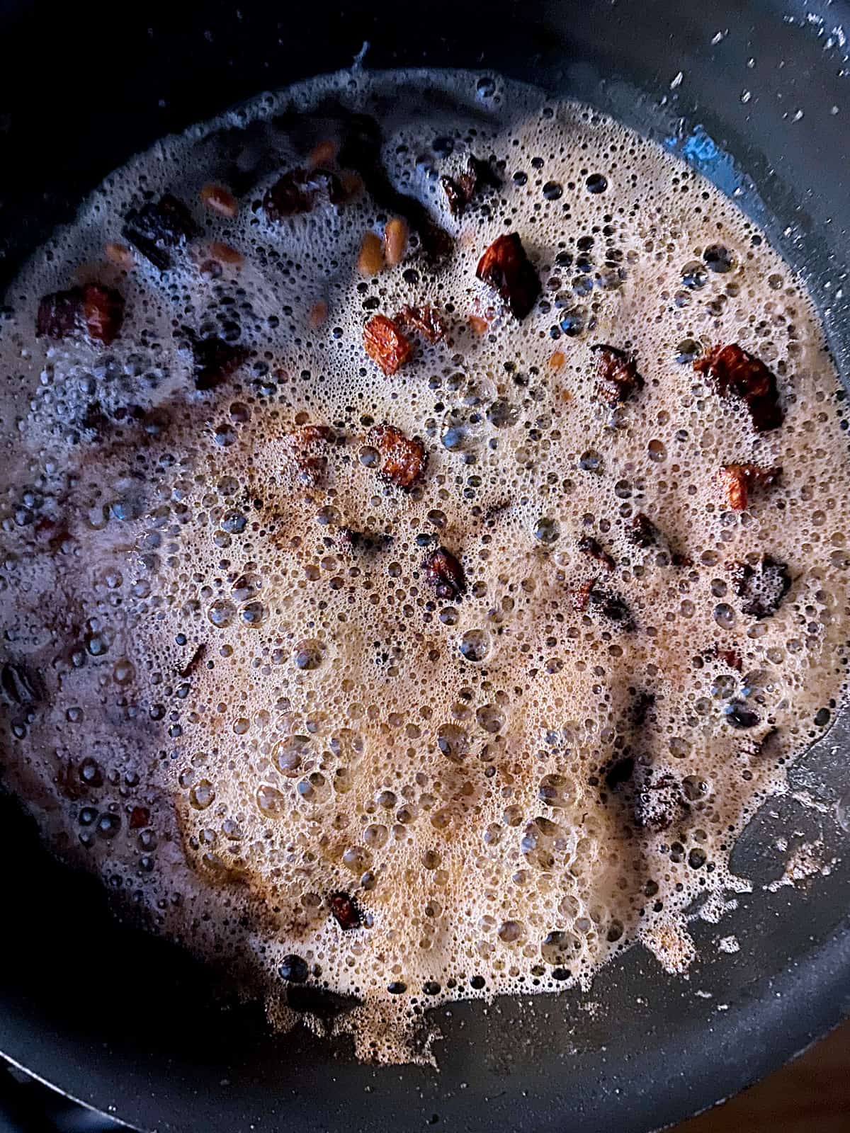 Brown butter sauce with capers and sundried tomatoes in a pan.