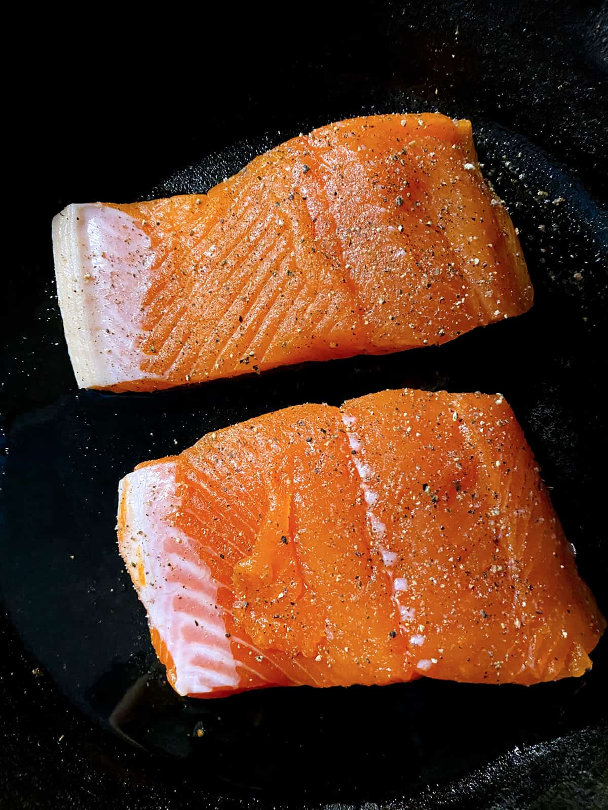 Two pieces of salmon cooking.