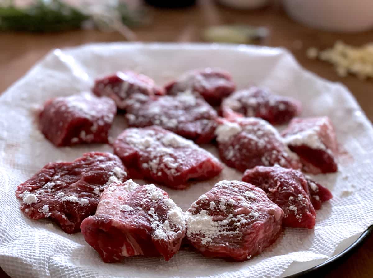 Pieces of beef dusted with flour on paper towel.