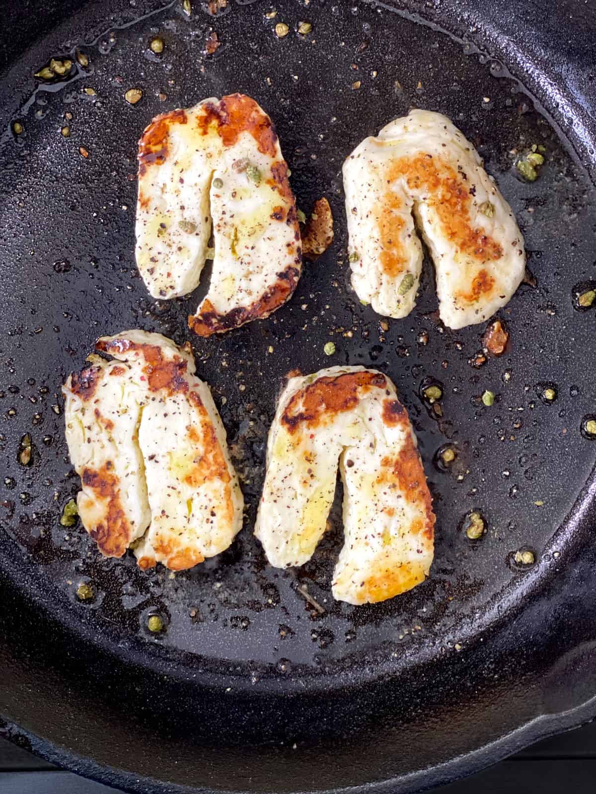 Two slices of halloumi cheese on cast iron.