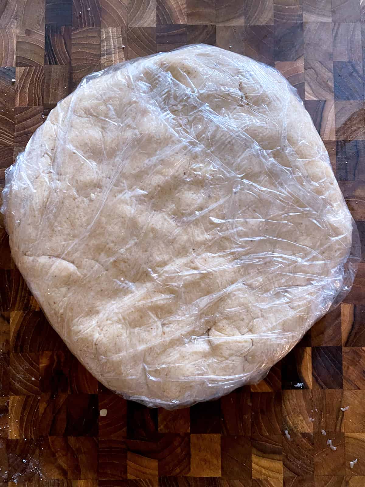 Savory galette dough wrapped in plastic wrap.