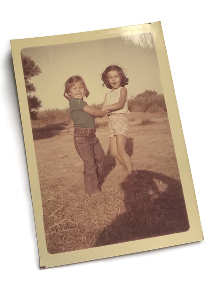 Two girls swirling in a field.