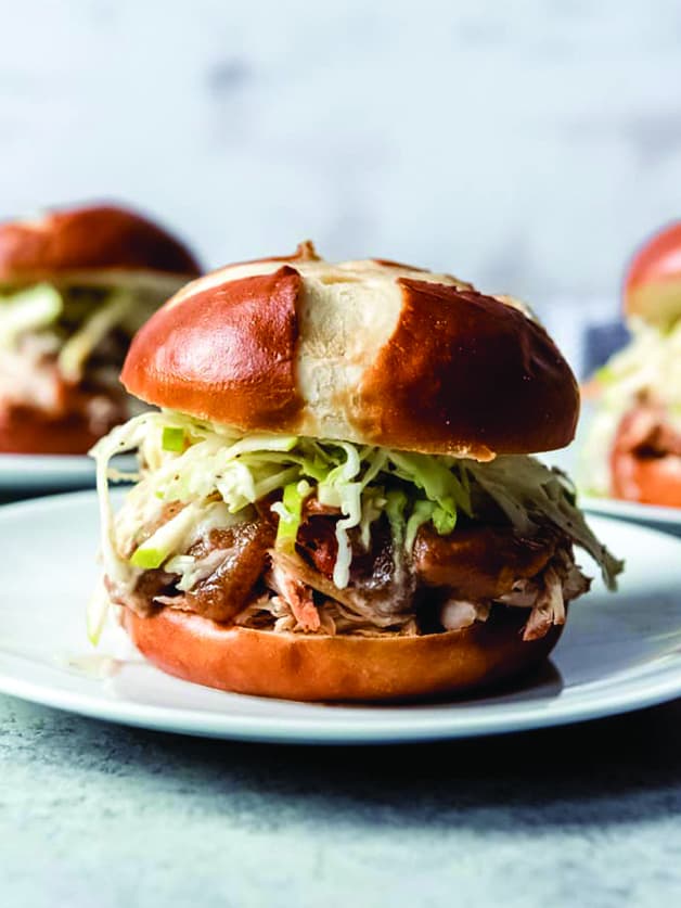 A pulled chicken sandwich with apple sauce and cabbage.