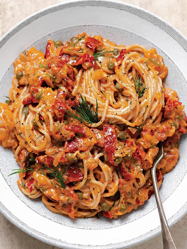 A plate with sun-dried tomato pasta sauce with dill, and capers.