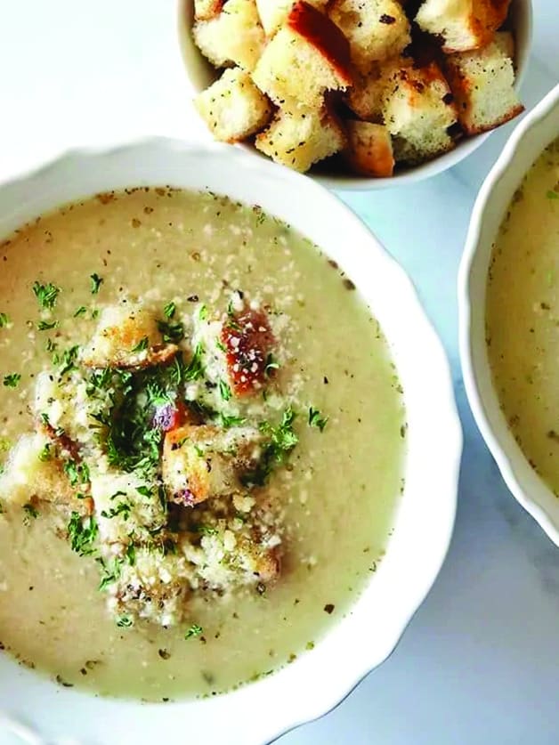 A bowl with roasted garlic soup and croutons.