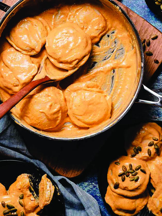 A skillet with pumpkin ravioli and a spoon.