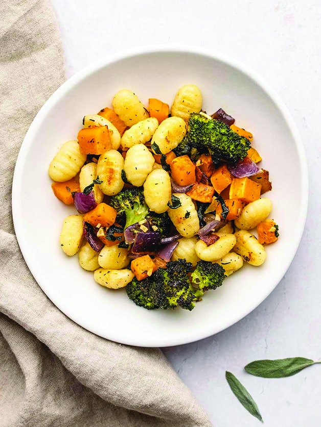 A plate with gnocchi, broccoli and squash.