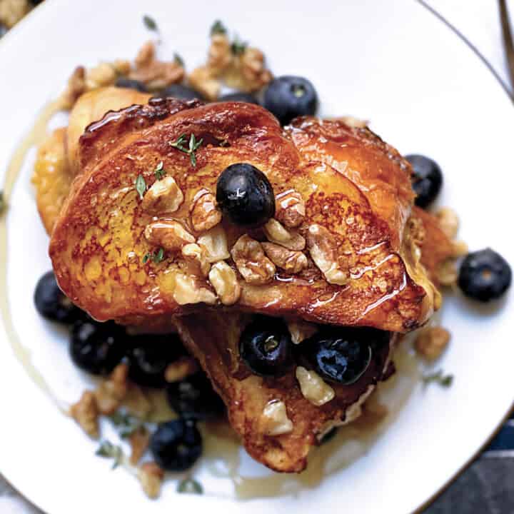 A plate with Tsoureki -greek brioche bread French toast blueberries, walnuts and honey.