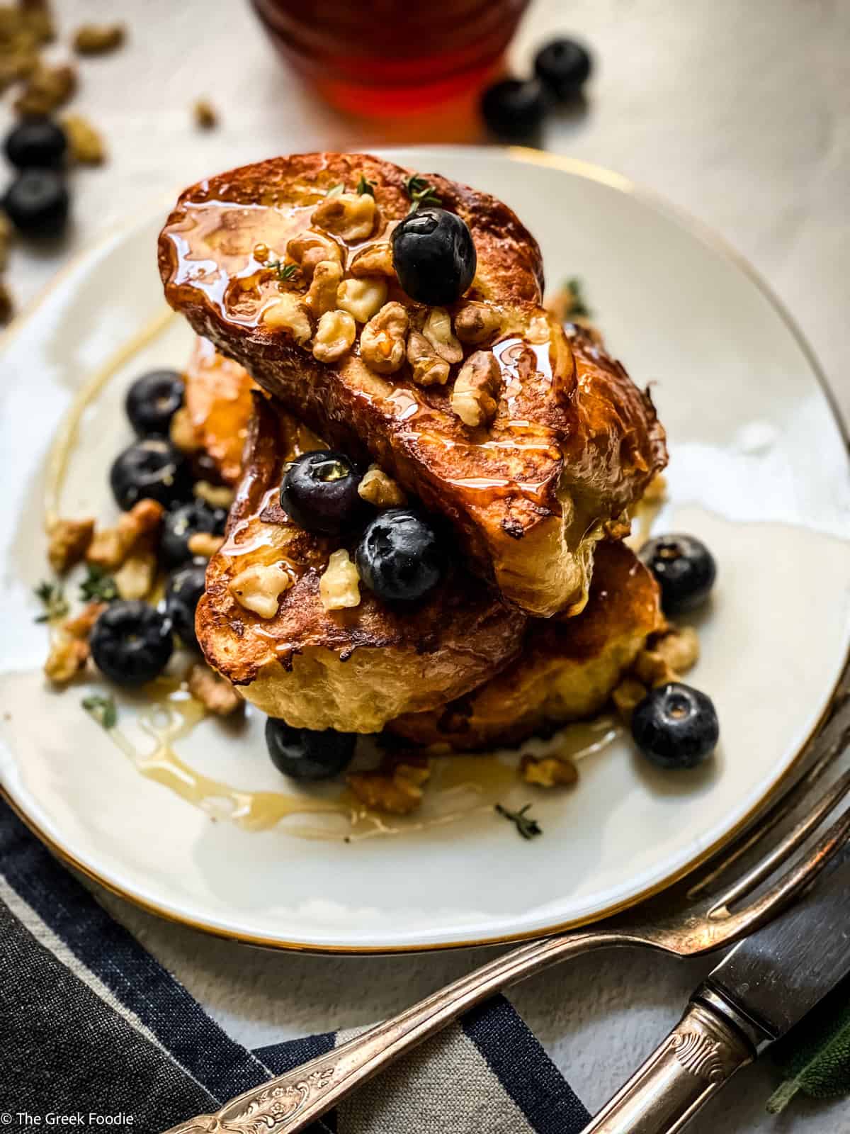 A plate with Tsoureki - Greek brioche bread French toast blueberries, walnuts and honey.