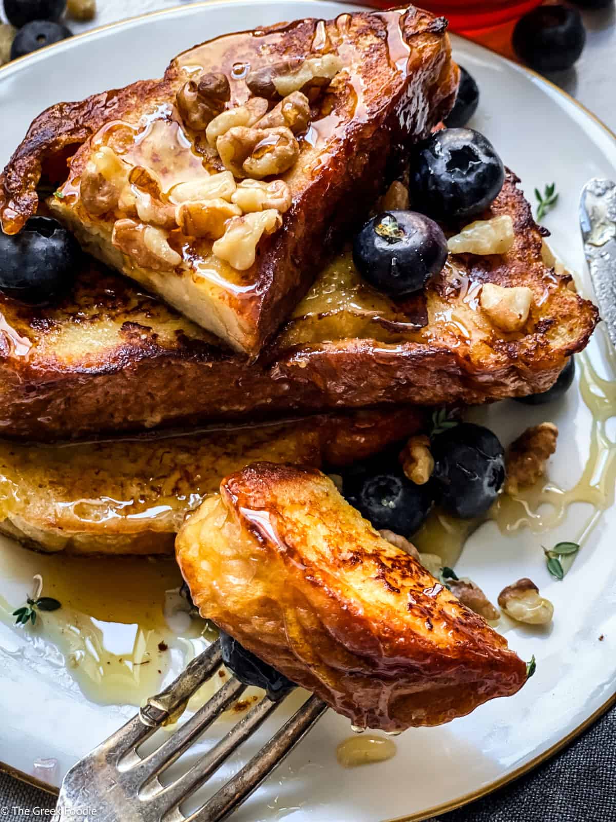 A plate with Tsoureki - Greek brioche bread French toast blueberries, walnuts and hone