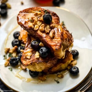 A plate with Tsoureki -Greek brioche bread French toast blueberries, walnuts and honey.