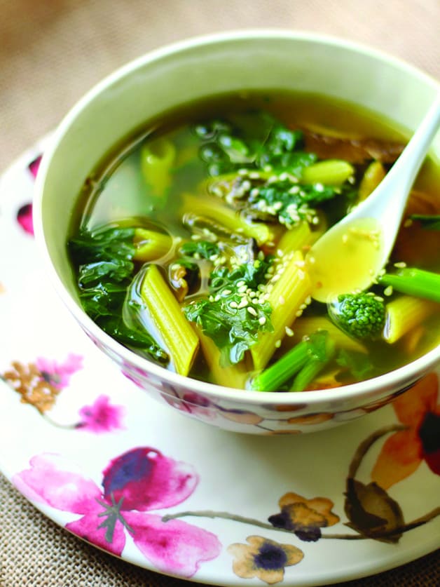 A bowl with  veggies, spices, and a bit of pasta soup, and a spoon.