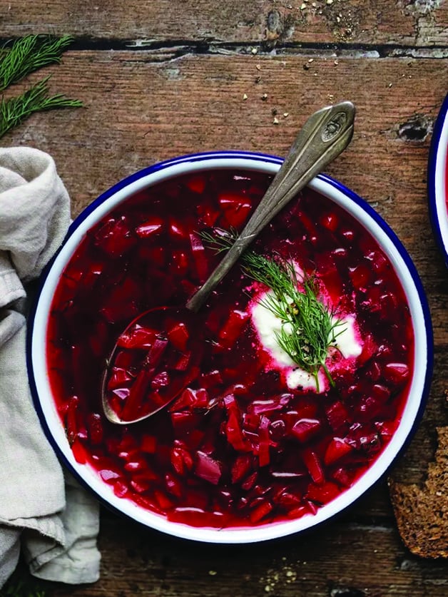 A bowl with vegetarian borscht soup and a spoon.