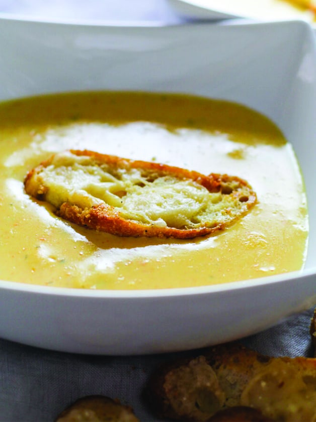 A bowl with cheese ssoup and a crouton.