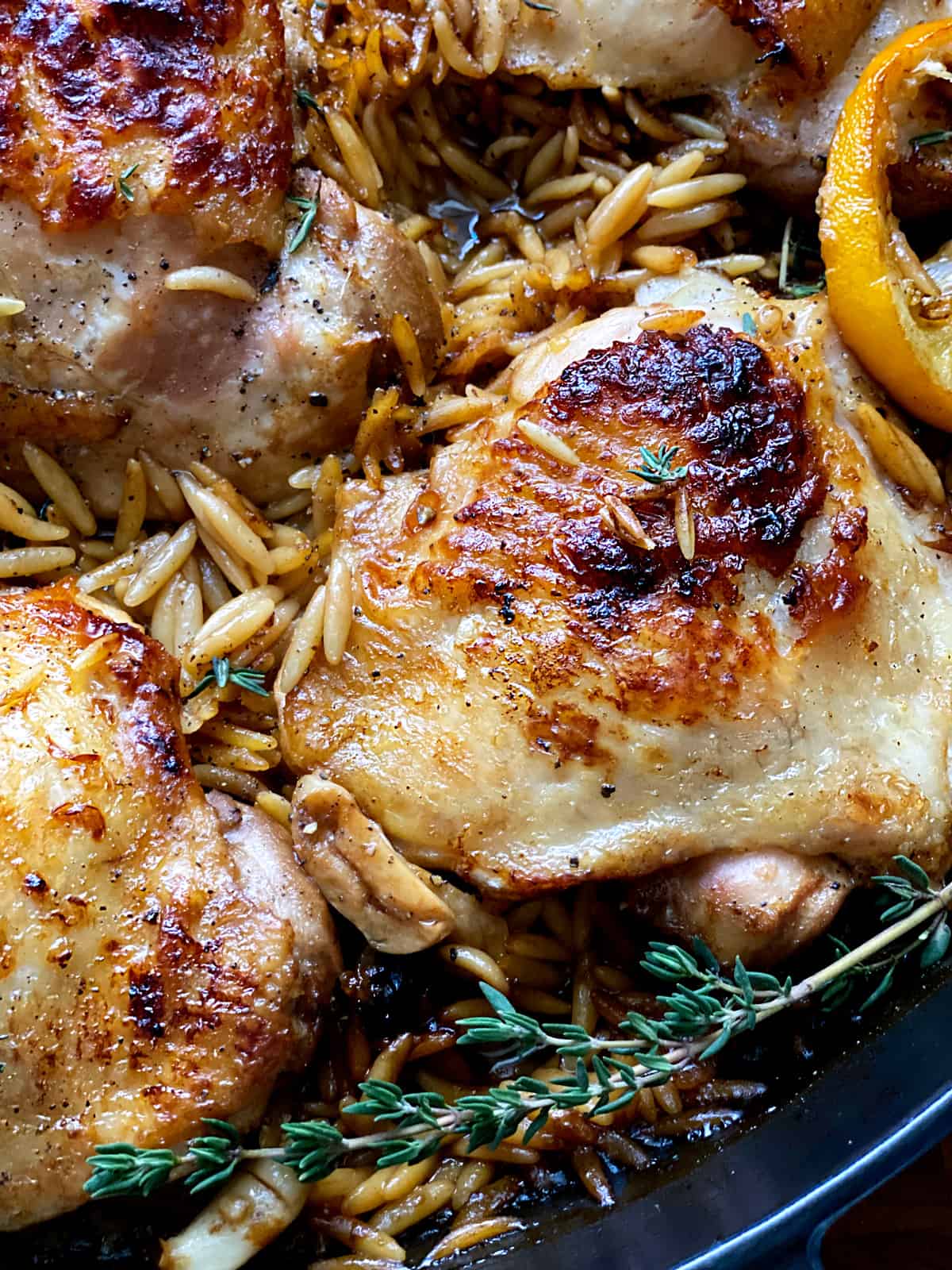 Butter milk chicken thighs with orzo in pan with a spoon.