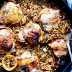 Butter milk chicken thighs with orzo in pan with a spoon.