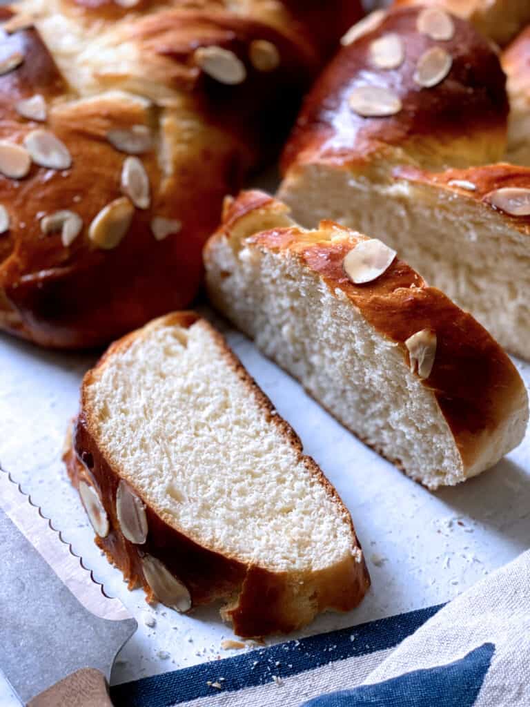 Two loaves of Tsoureki and a couple of slices on a table.
