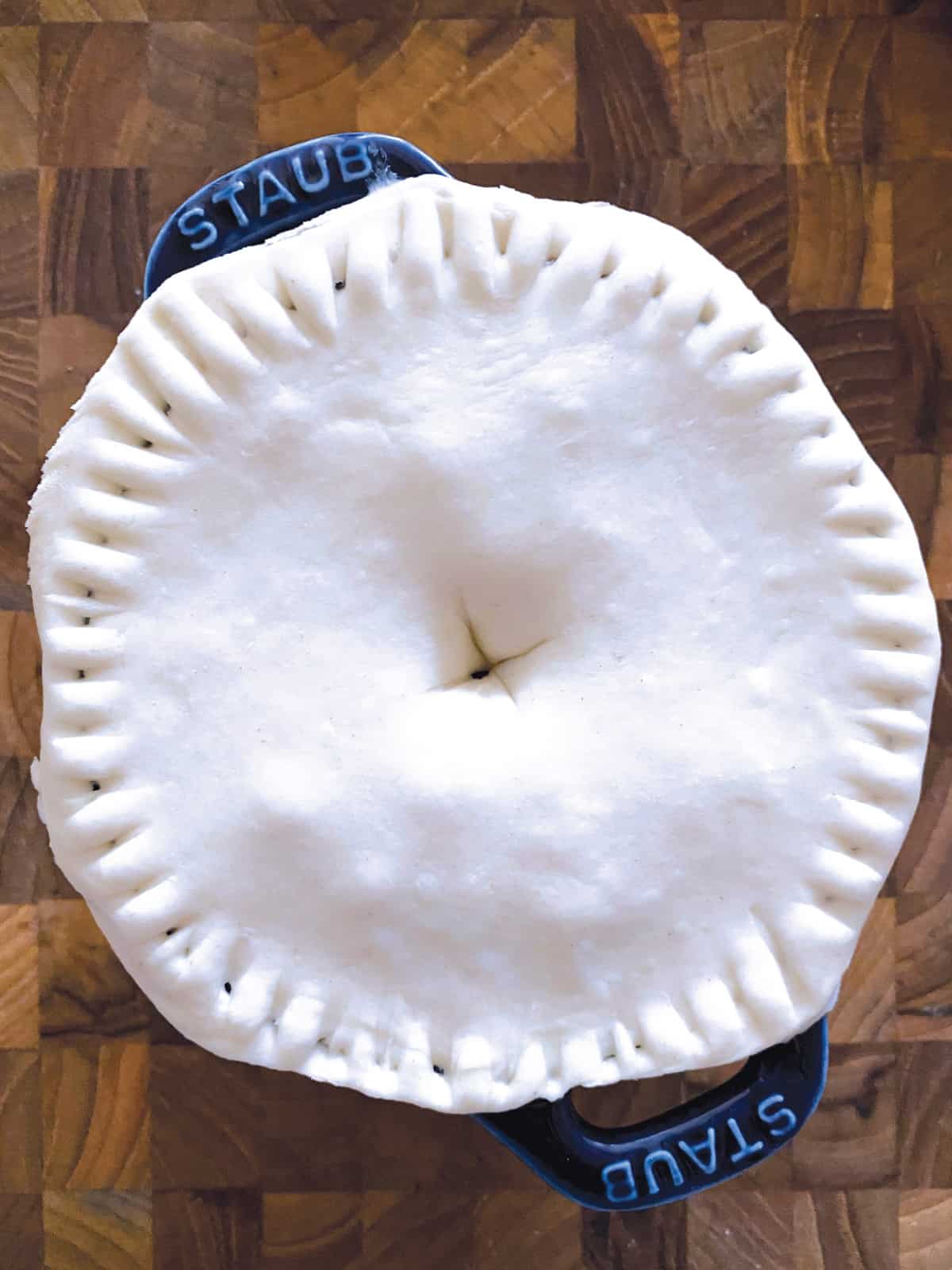 A mini pie with puff pastry on a cutting board.