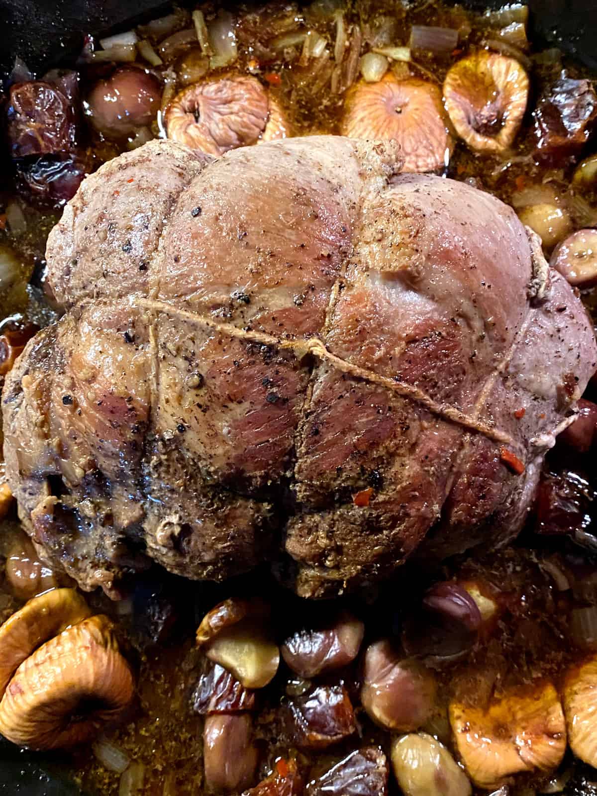 A A pork shoulder roast tied with twine with dried fruit.