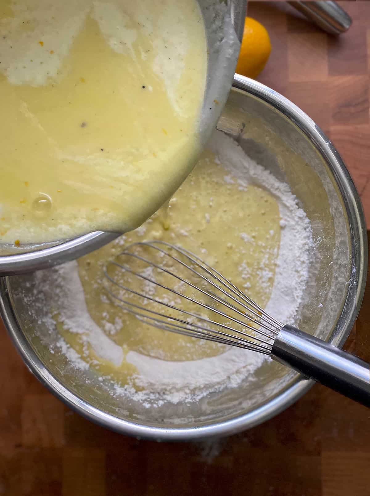 Pouring eggs and sugar mixture into a bowl with flour.